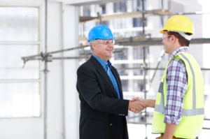 A man in a suit shaking the hand of the foreman on a construction site